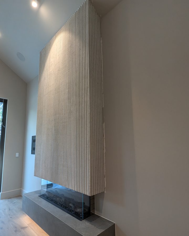 A fluted cream fireplace wall rising to a vaulted ceiling.