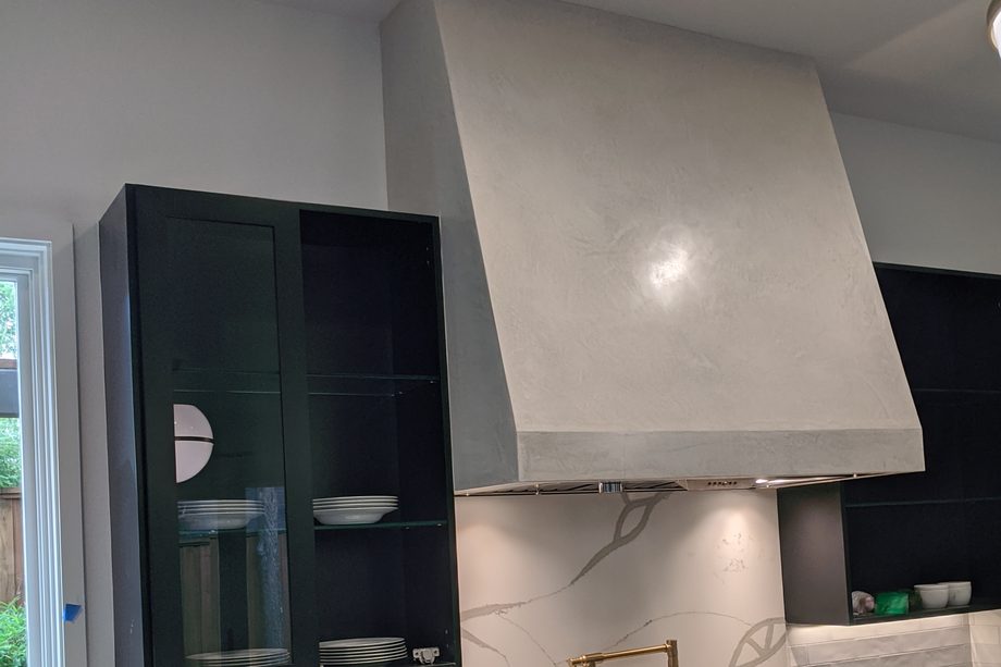 A smooth pale range hood in a modern kitchen.