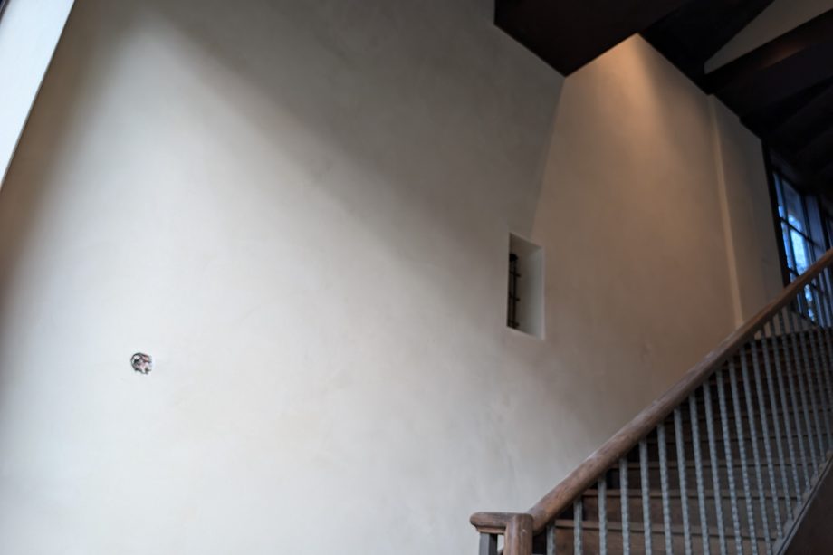 A tall smooth cream wall beside a staircase.