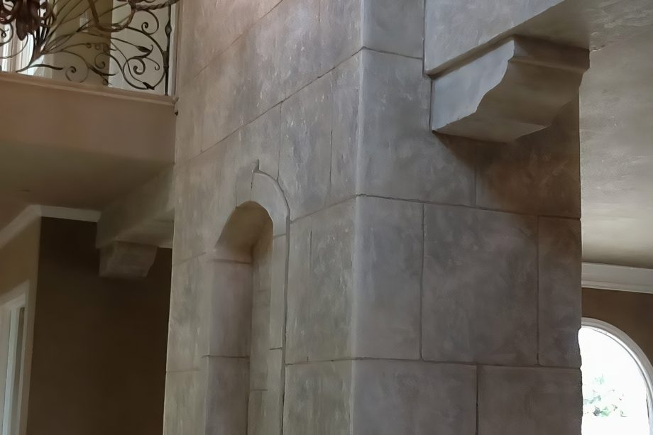 A coated stone-block wall with a corbel and an arched niche.