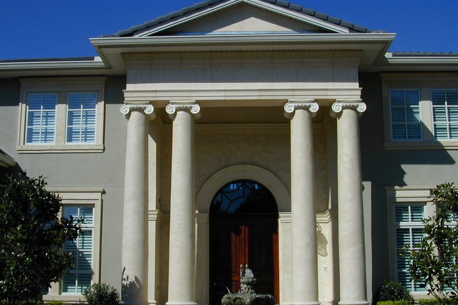 A portico of four tall columns in pale coated stone.
