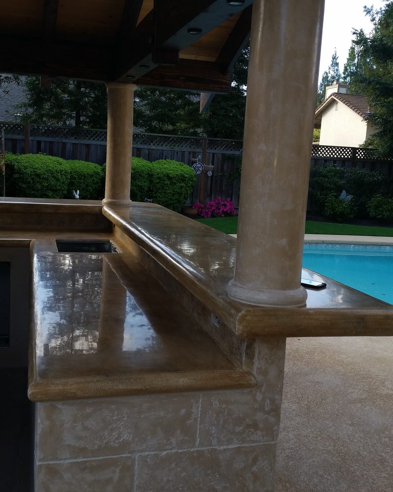 An outdoor bar and column in coated stone beside a pool.