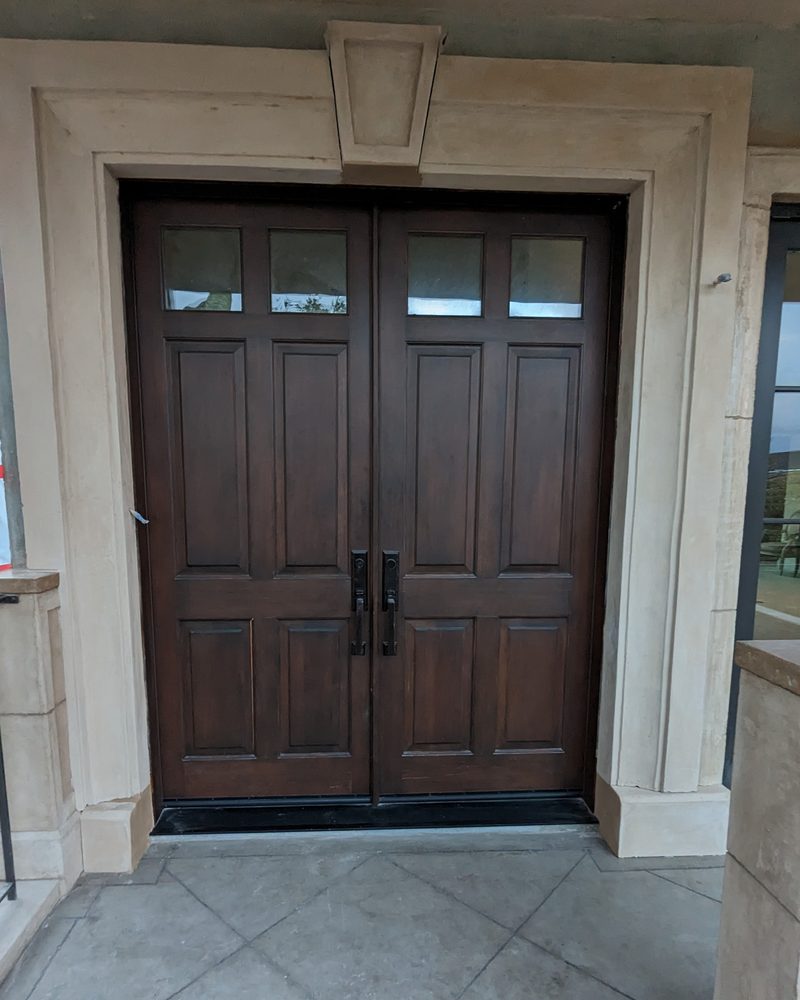 A double front door in a coated surround with a keystone.