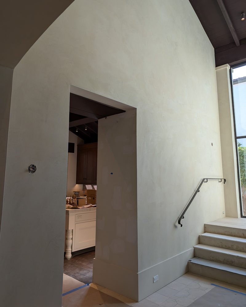 A tall cream wall with a squared doorway and steps.
