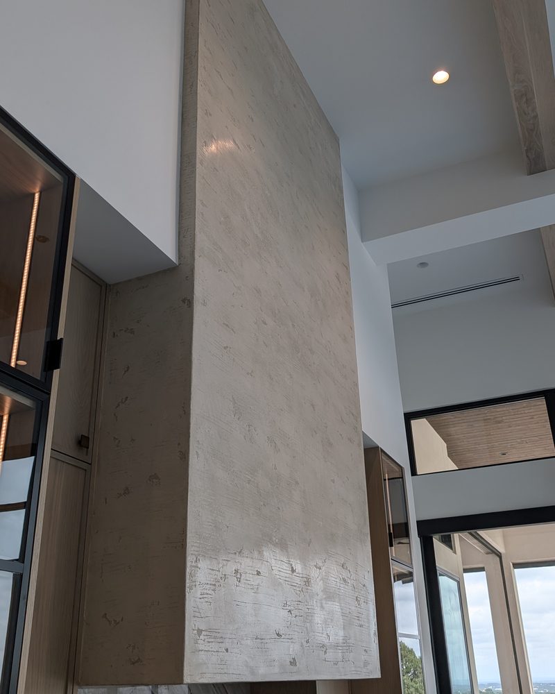 A tall coated column in a modern room with steel-framed windows.