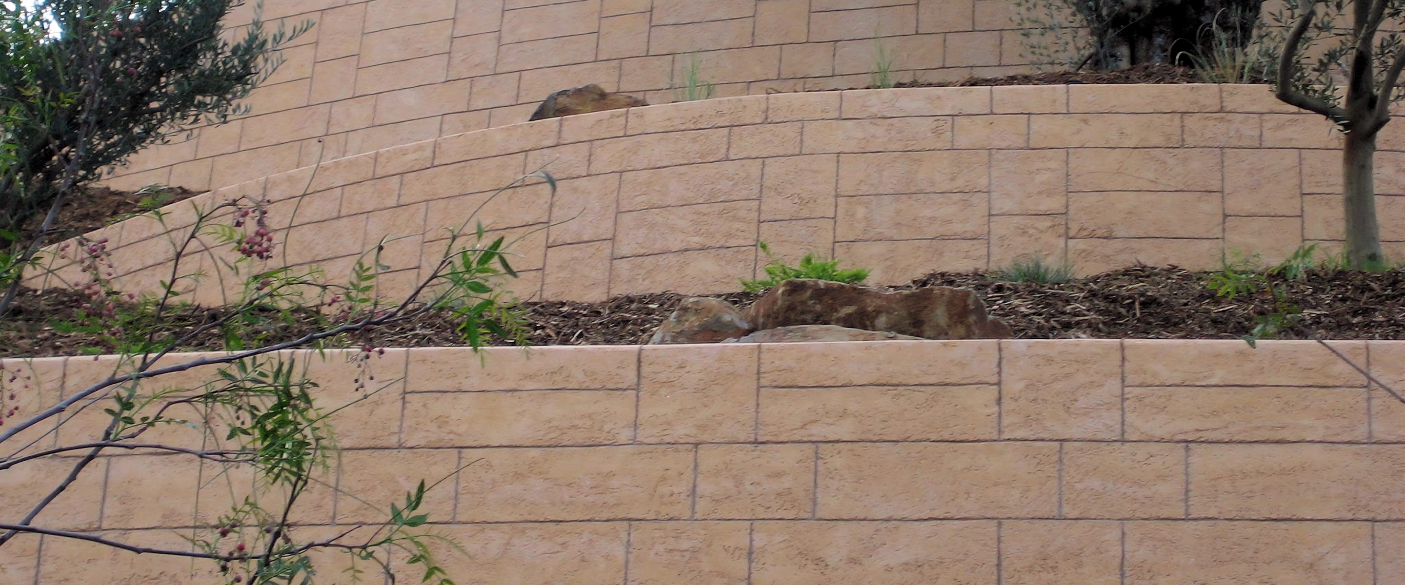 Terraced retaining walls in scored tan coated stone.