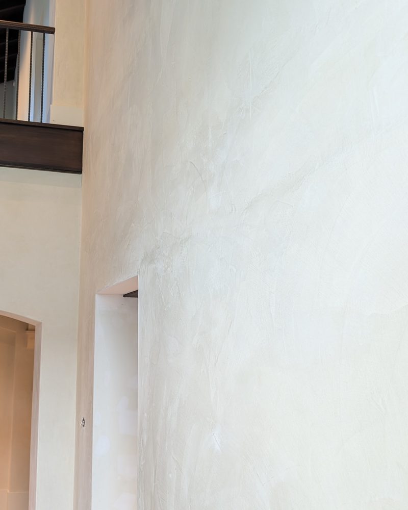 A tall smooth pale wall in a two-storey foyer.
