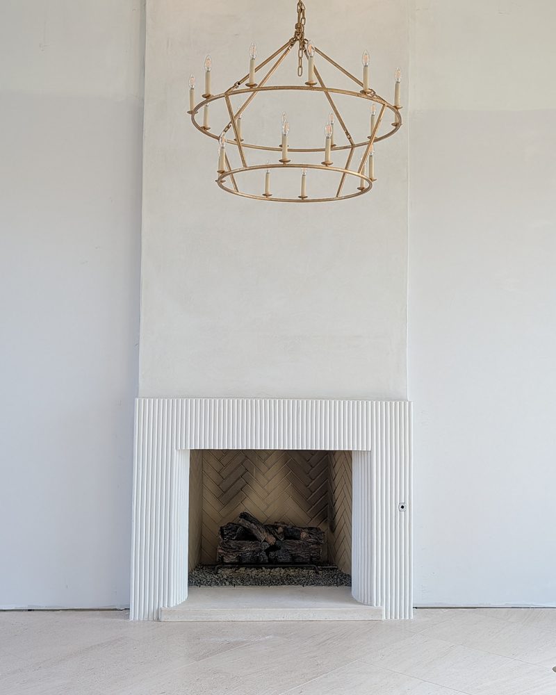 A tall pale chimney breast with a fluted fireplace surround.