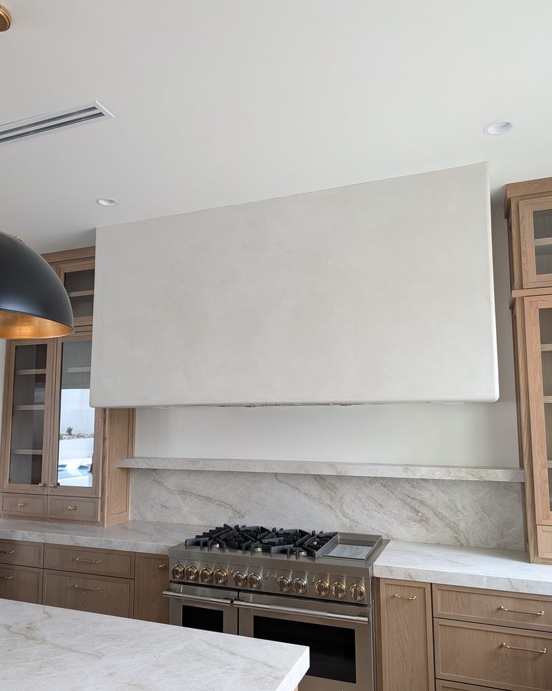 A smooth pale range hood above a kitchen range.