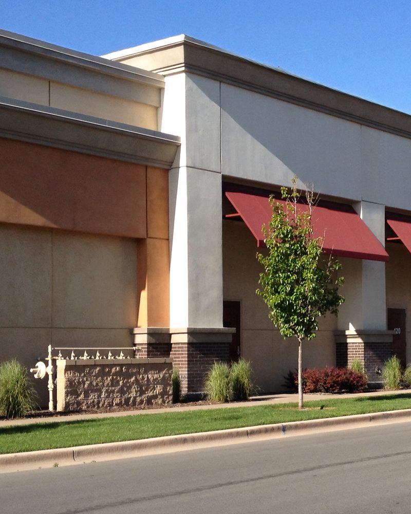 A commercial streetscape in coated stone with red awnings.