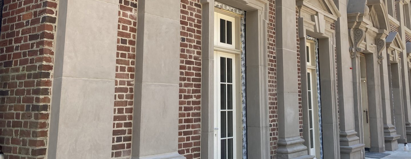 A colonnade of pilasters and door surrounds in Arcus Plaster on a brick facade.
