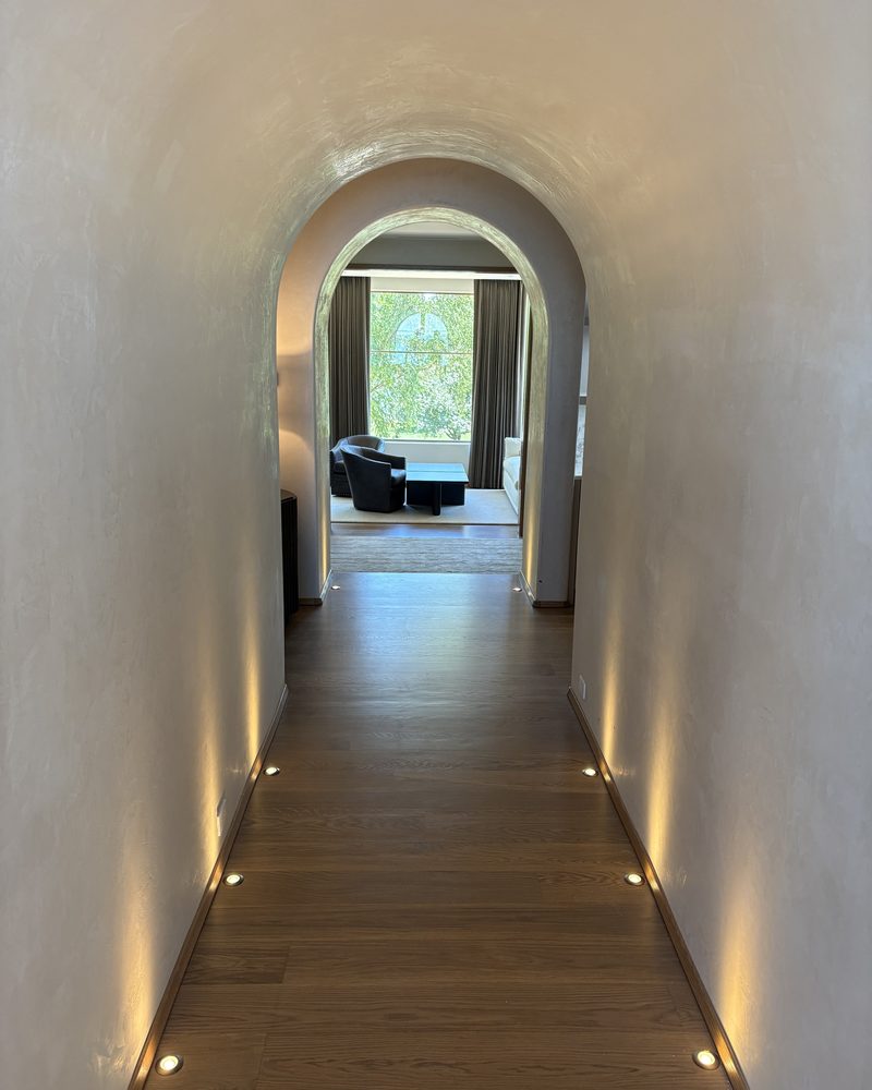 A long arched hallway in Lime Plaster Fine, lit at the floor.
