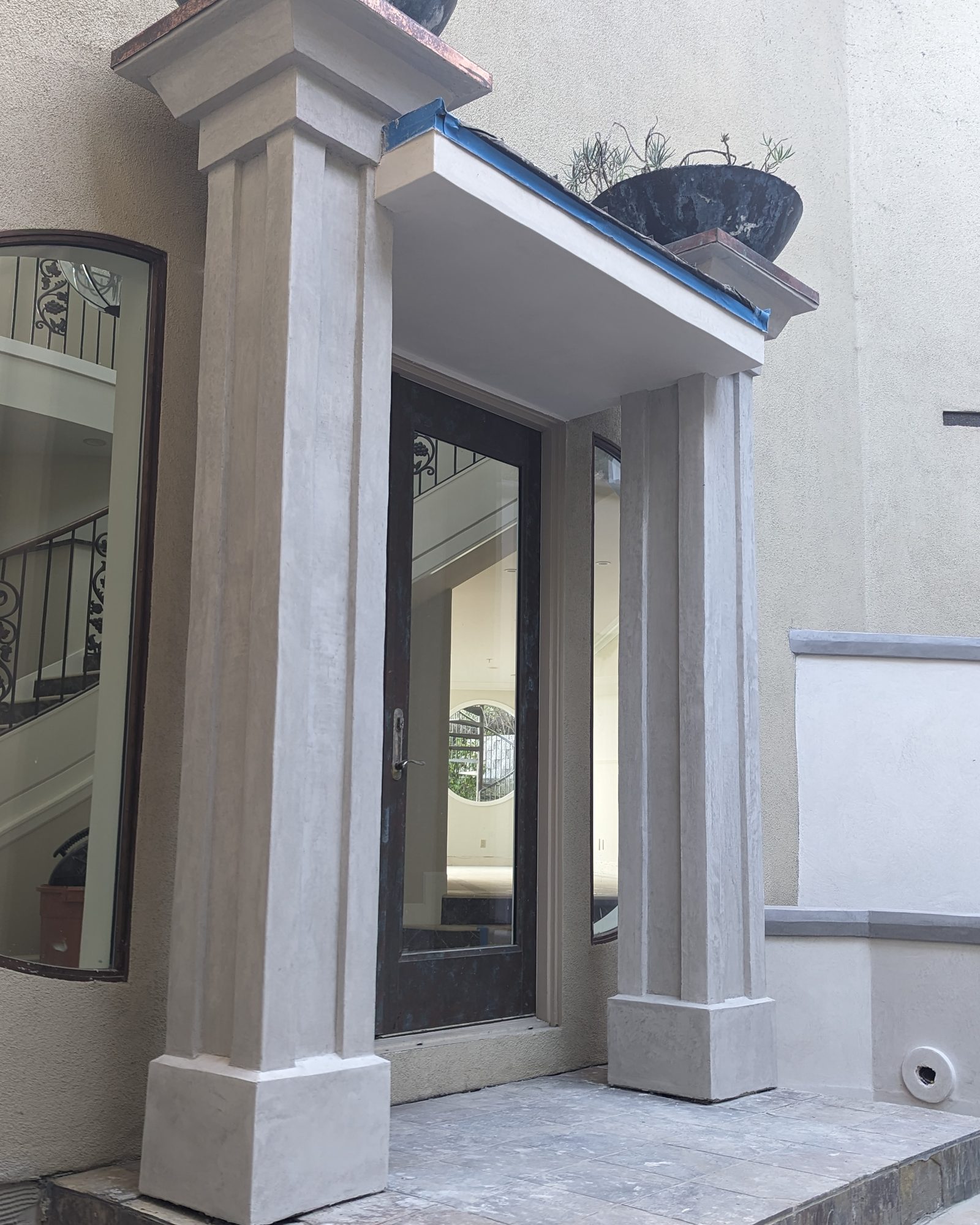 A coated-stone entry portico with square columns.