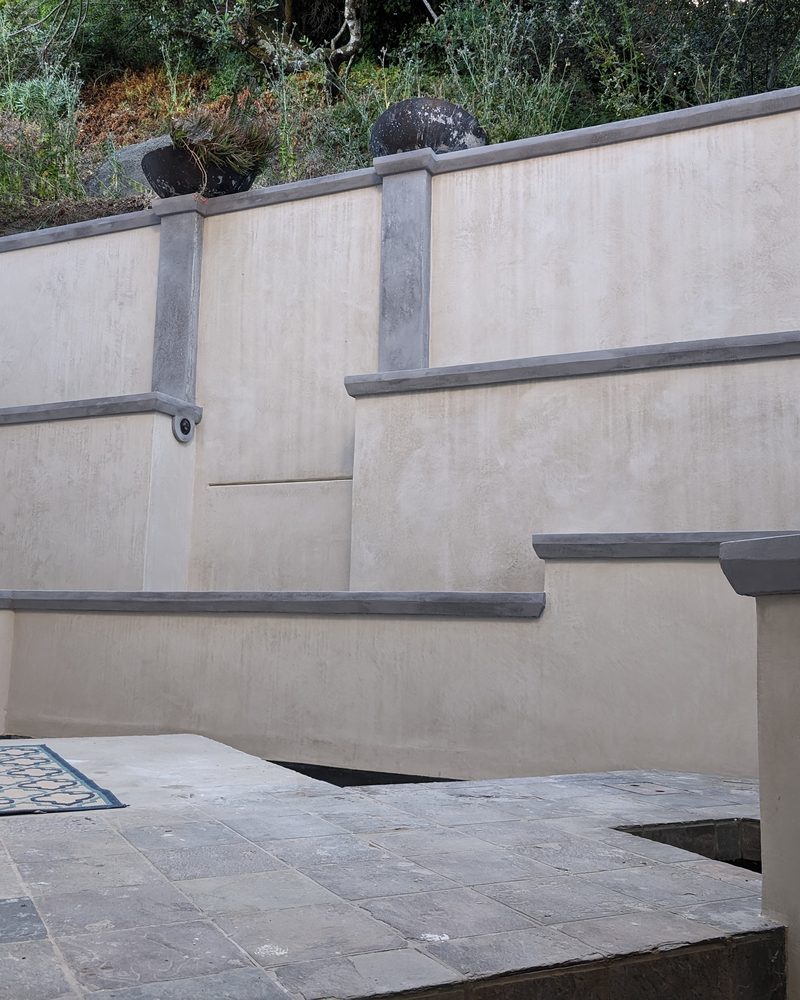 Stepped exterior terrace walls in cream coated stone with grey caps.