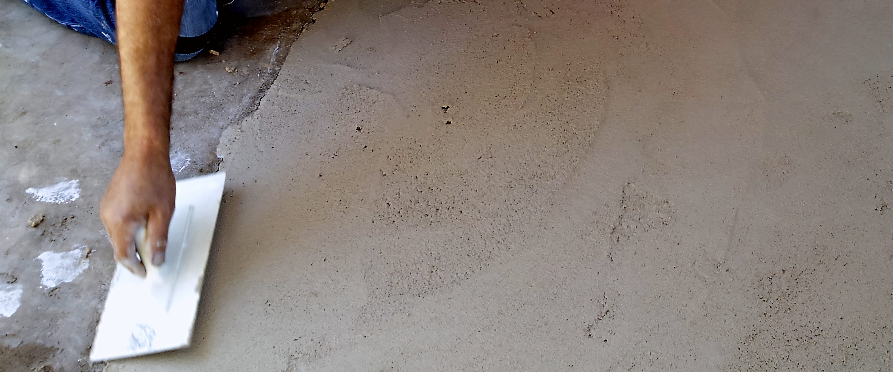 An applicator's hands trowelling fresh plaster.