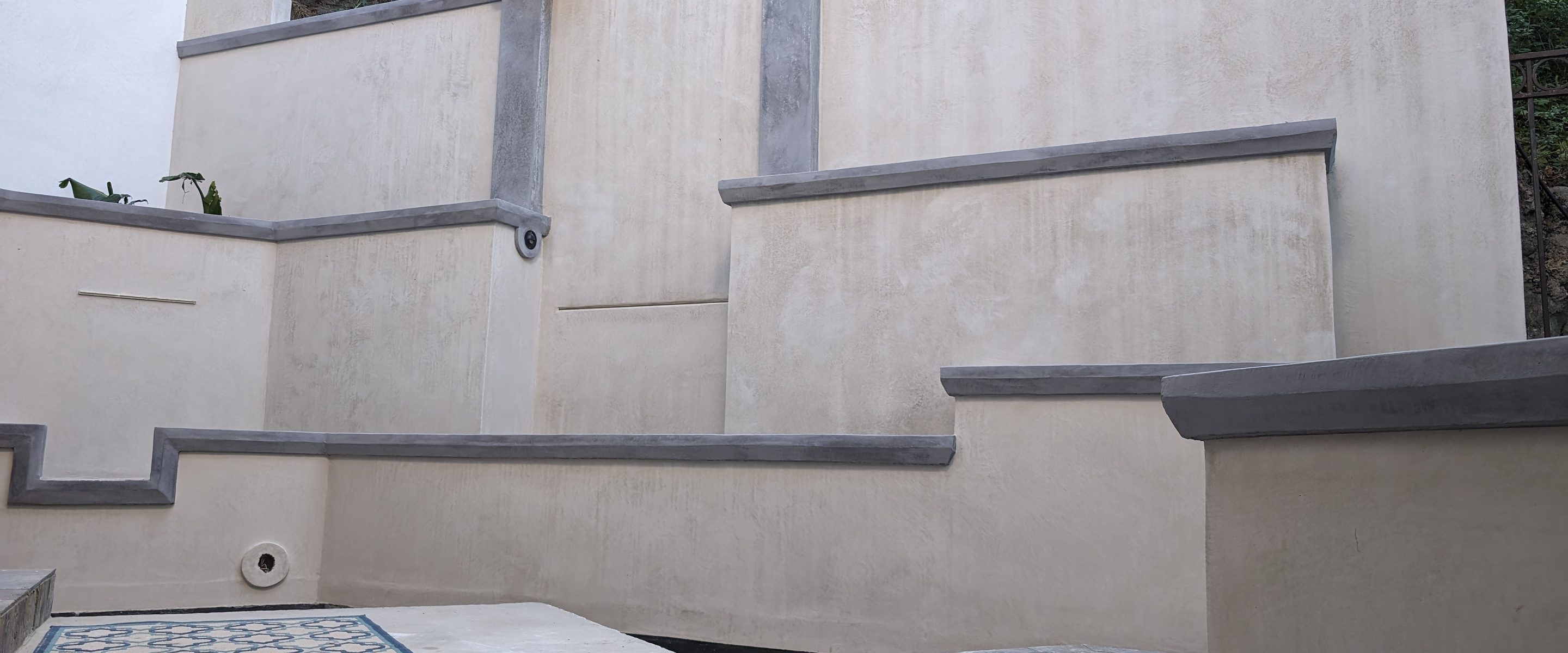 Stepped exterior terrace walls in cream coated stone with grey caps.