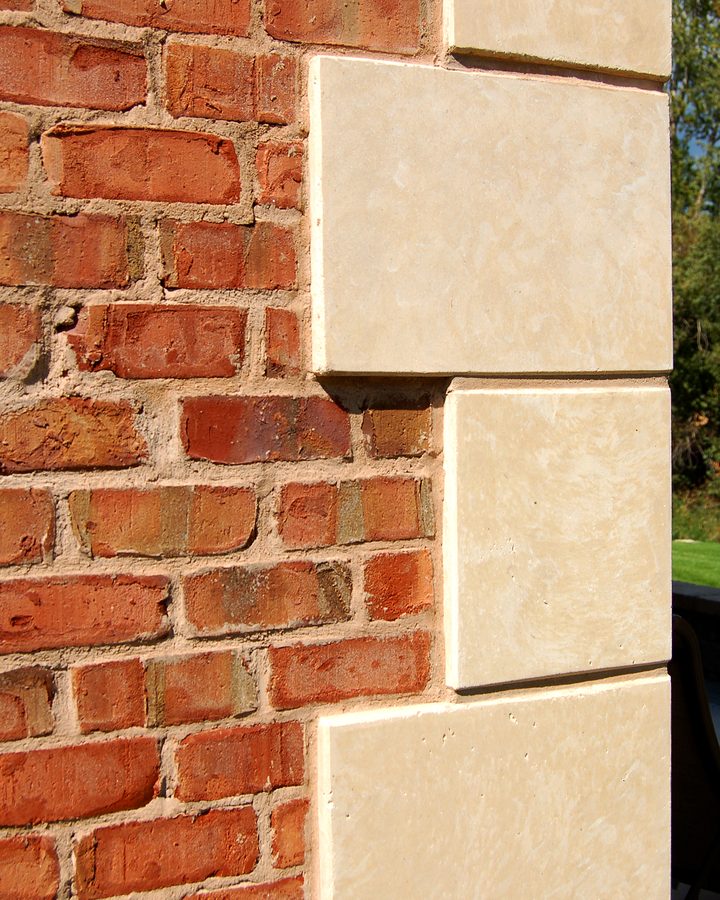 Cream coated-stone quoins against a red brick corner.