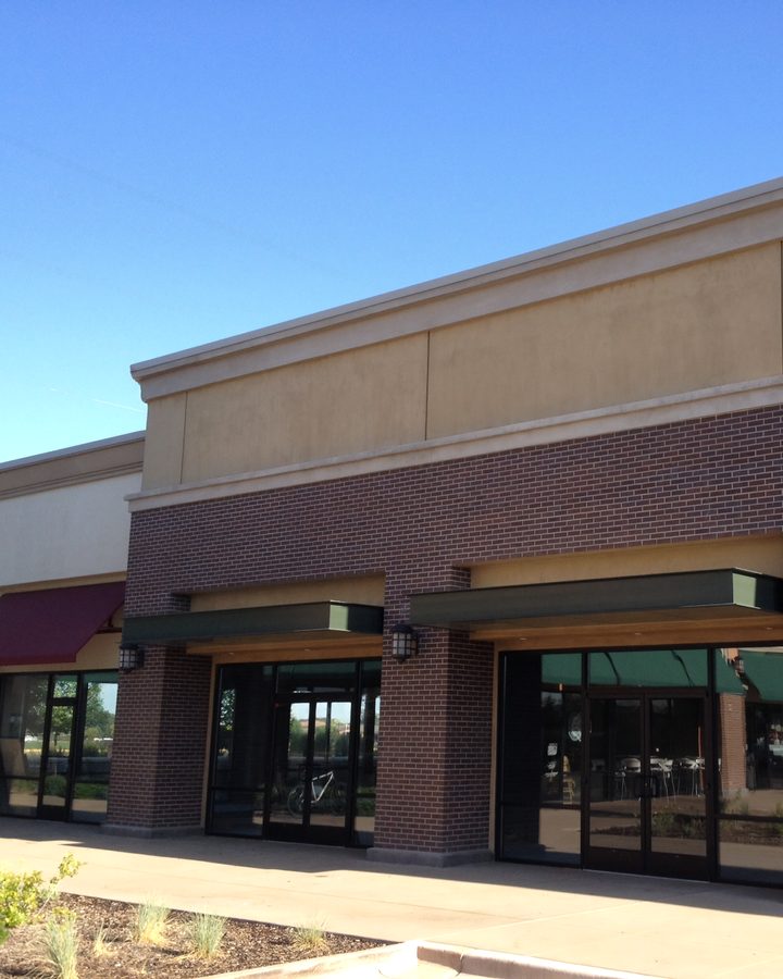 A storefront row with cream coated parapets between brick piers.