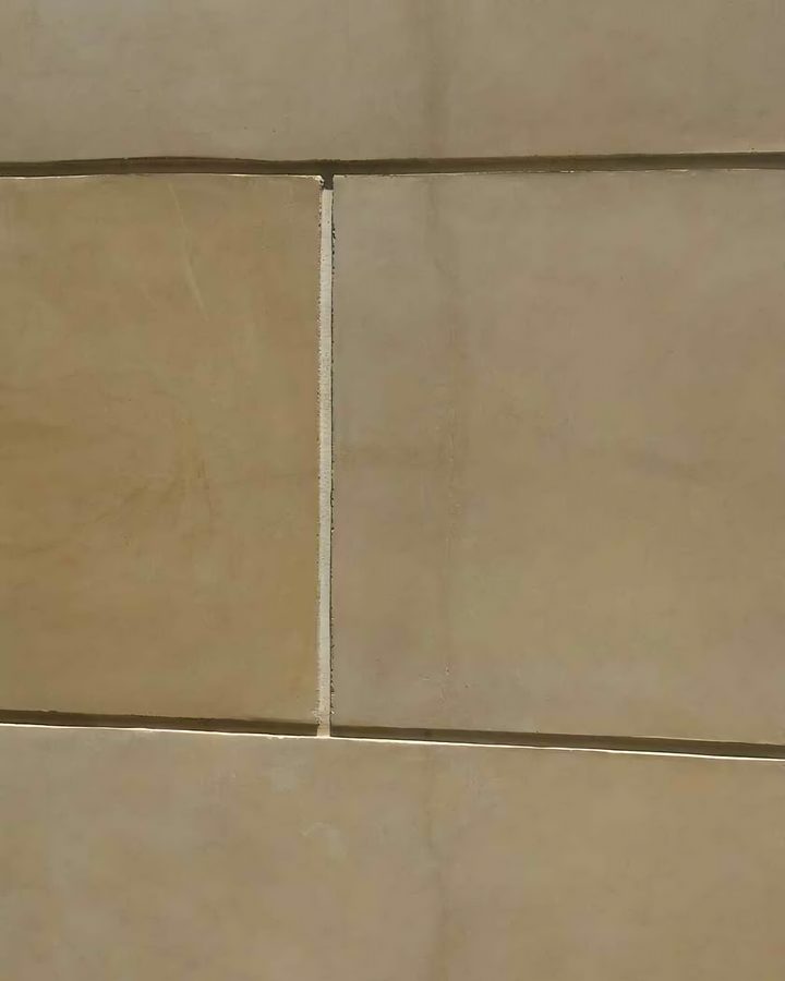 Tan coated-stone wall panels with fine joints.