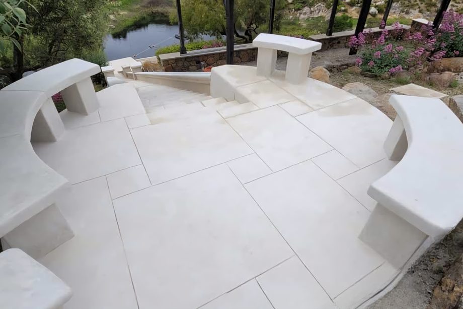 A curved terrace with coated benches above a pond.